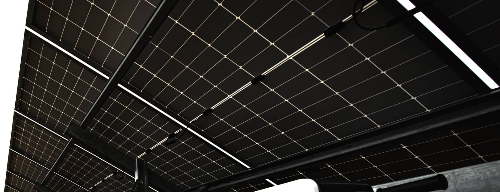 Güneş paneli sıralarının altından görünüm; sağda inverter panoları.